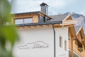 A building with a mountain view, wooden balconies, and a sign reading 'Ciasa Apartments LAVARELLA.'