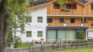 Un immeuble de deux étages avec une façade en bois, des balcons ornés de jardinières et une enseigne indiquant « Clasa Lavarella Apartments ».