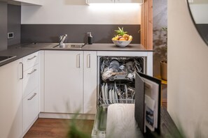 A modern kitchen with white cabinets, a stainless steel sink, and a dishwasher.