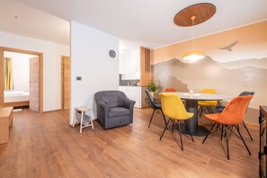 A modern living room with a dining area, wooden flooring, and a mountain-themed wall mural.