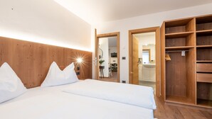 Une chambre à coucher avec une tête de lit en bois, un grand lit avec une literie blanche et une armoire en bois.