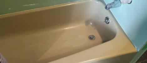 Una bañera con desagüe, grifo y ducha.