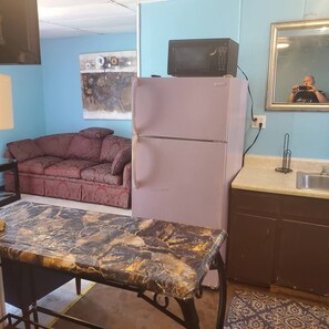A compact kitchen with a refrigerator, a microwave, a sink, and a dining table. - Rustic1BRPet&420 Friendly2.5blocksToBoardsSeptSpecialsProm&SeniorWks22Under25ok (Wildwood)