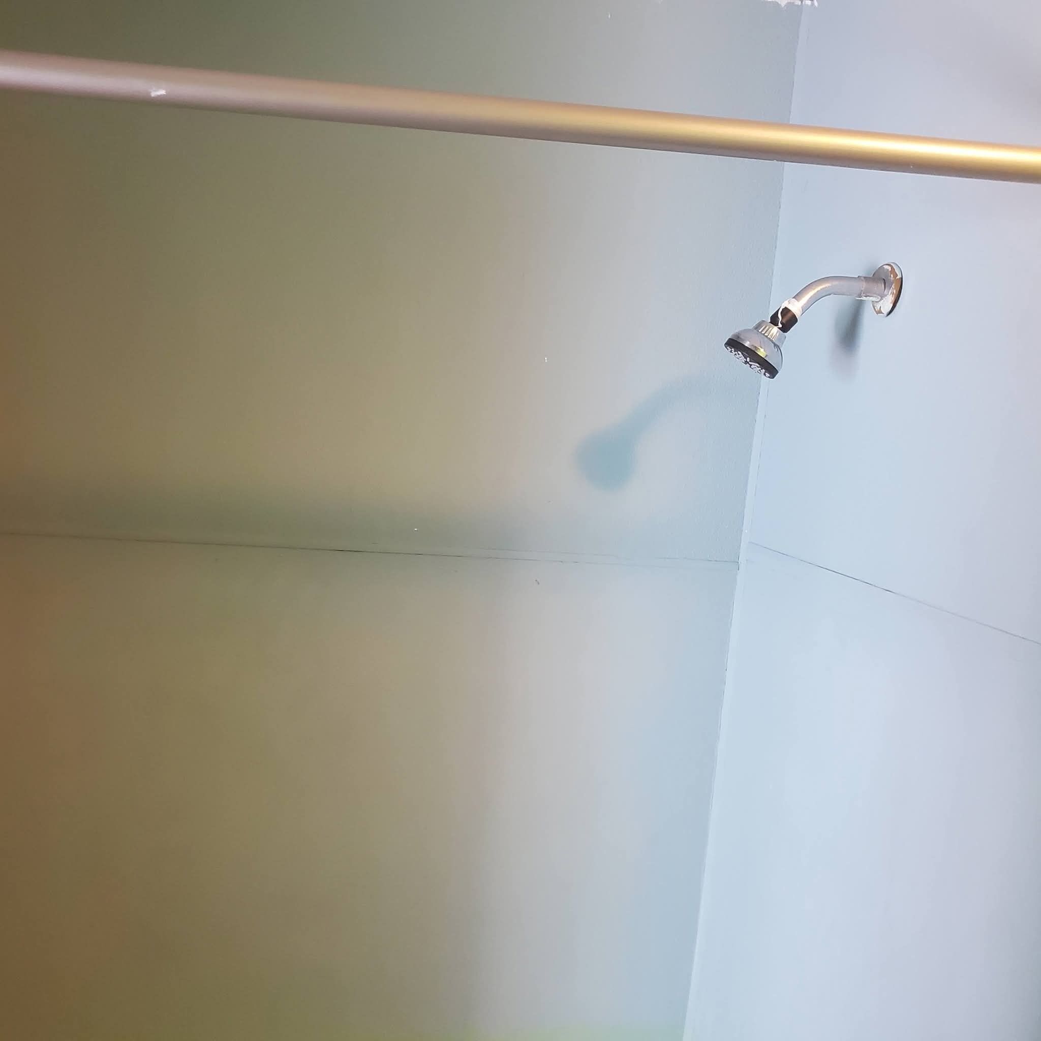 A shower with a handheld showerhead and a horizontal bar across the top.