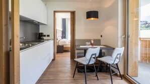 Una cucina moderna con mobili bianchi, una macchina da caffè e un'area pranzo con due sedie e un tavolo.