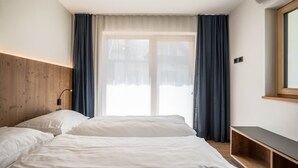 Una camera d'albergo con un letto, un comodino, una lampada e una finestra con tende.