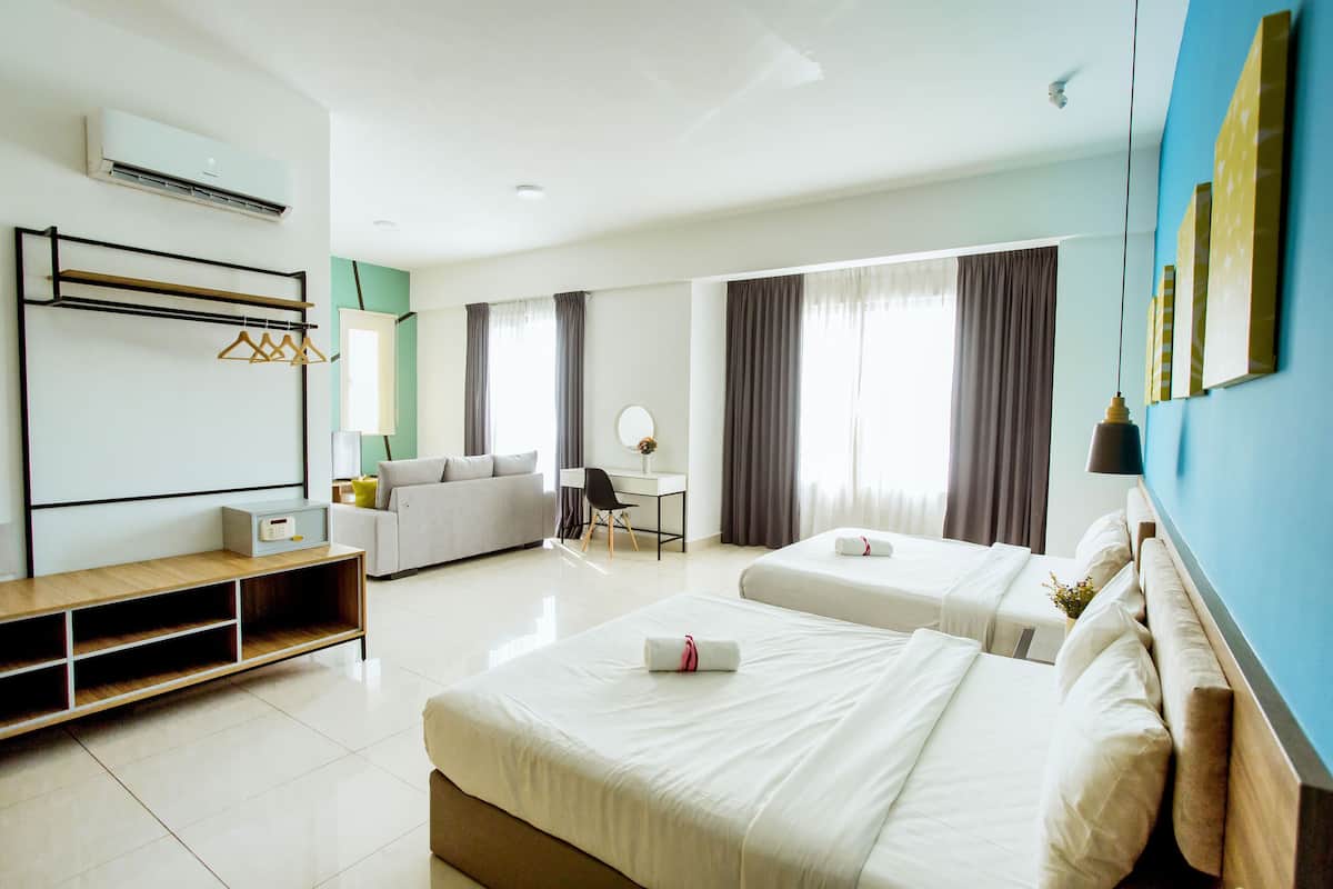 A hotel room with two beds, a desk, a sofa, and a wardrobe.