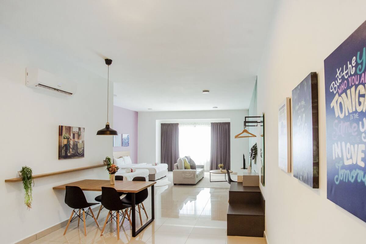 A modern living room with a dining area, a staircase, and a large motivational poster on the wall.