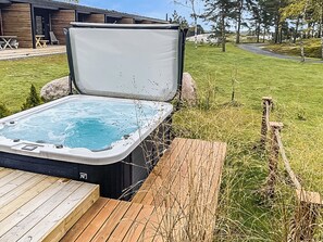 A hot tub on a wooden deck with a grassy area and a building in the background. - Kasnäs marina a 7 by Interhome (Kemiönsaari)