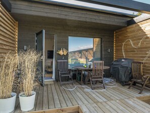A wooden deck with a table and chairs, a barbecue grill, and potted plants. - Kasnäs marina a 7 by Interhome (Kemiönsaari)