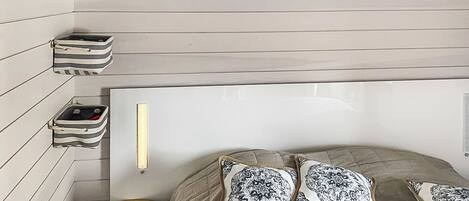 A bedroom with a bed, two pillows, a bedside table, and a lamp.