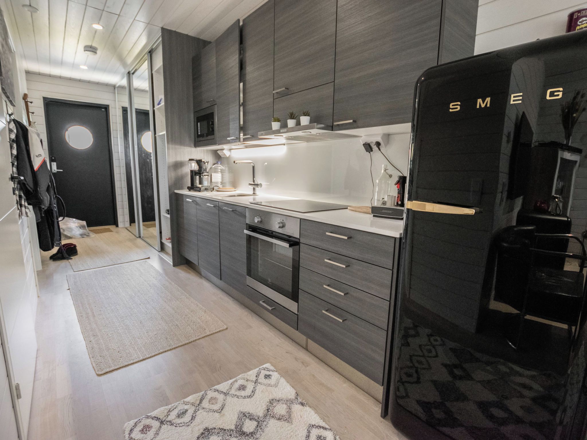 Une cuisine moderne avec des meubles de rangement sombres, un four encastré et un réfrigérateur.