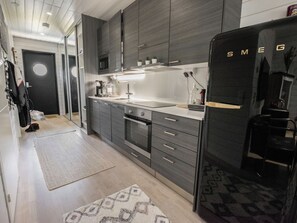 Una cocina moderna con armarios oscuros, horno empotrado y refrigerador.