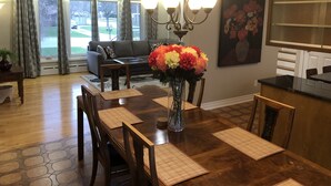 A dining area with a wooden table, chairs, a vase of flowers, and a chandelier. - Niagara Executive Luxury - HUGE, Warm, Cozy and Clean 3 Bed, 1 Bath SuiteStay(1) (Welland)