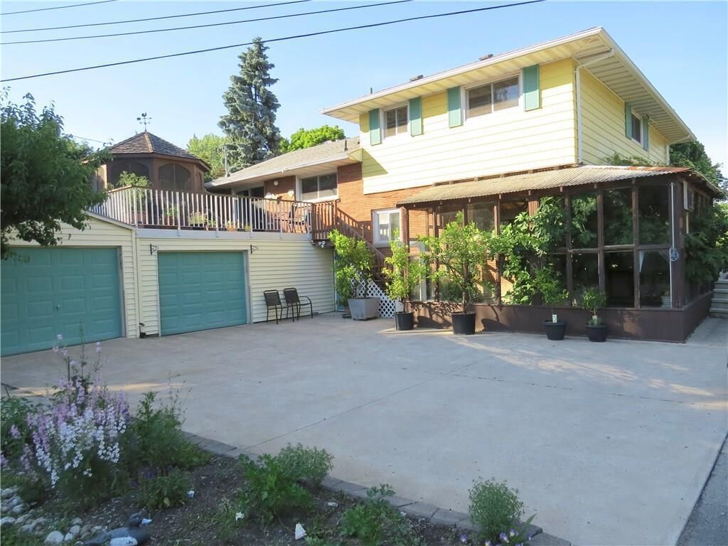 Een huis met twee verdiepingen, een overdekte patio, een omheinde achtertuin en een garage.
