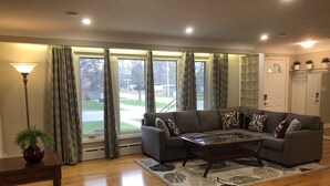 A living room with a grey sofa, a wooden coffee table, a floor lamp, and a potted plant. - Niagara Executive Luxury - HUGE, Warm, Cozy and Clean 3 Bed, 1 Bath SuiteStay(1) (Welland)