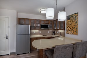 A modern kitchen with a stainless steel refrigerator, a microwave, a sink, and a dining area with a table and chairs. - Staybridge Suites Phoenix East - Gilbert, an IHG Hotel (Gilbert)