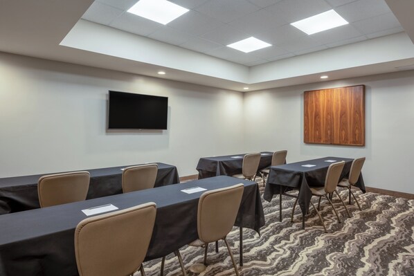 A conference room with tables, chairs, a flat-screen TV, and a wooden accent wall. - Staybridge Suites Phoenix East - Gilbert, an IHG Hotel (Gilbert)