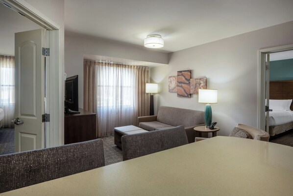 A hotel room with a bed, a desk, a chair, a sofa, a TV, and a lamp. - Staybridge Suites Phoenix East - Gilbert, an IHG Hotel (Gilbert)