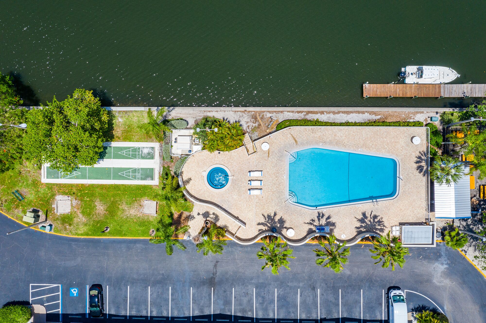 Vista aèria d'un complex turístic amb piscina, pistes de tennis i zona d'aparcament.
