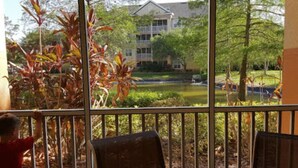 A view from a balcony with a table and chairs, overlooking a landscaped garden and a building with multiple windows. -   $899/OBO, 2 Br/2Ba for 8, Balc, Kit (Orlando)