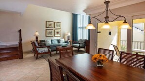 A dining area with a wooden table, chairs, and a chandelier. There is a sofa and a coffee table in the background. -   $899/OBO, 2 Br/2Ba for 8, Balc, Kit (Orlando)