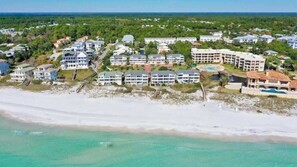 A coastal resort with beachfront villas, a central pool area, and a large building with multiple balconies.