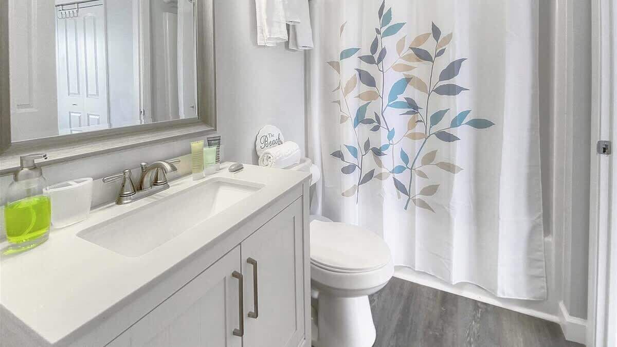 A bathroom with a white sink, mirror, and toilet.