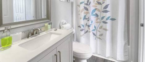 A bathroom with a white sink, mirror, and toilet.
