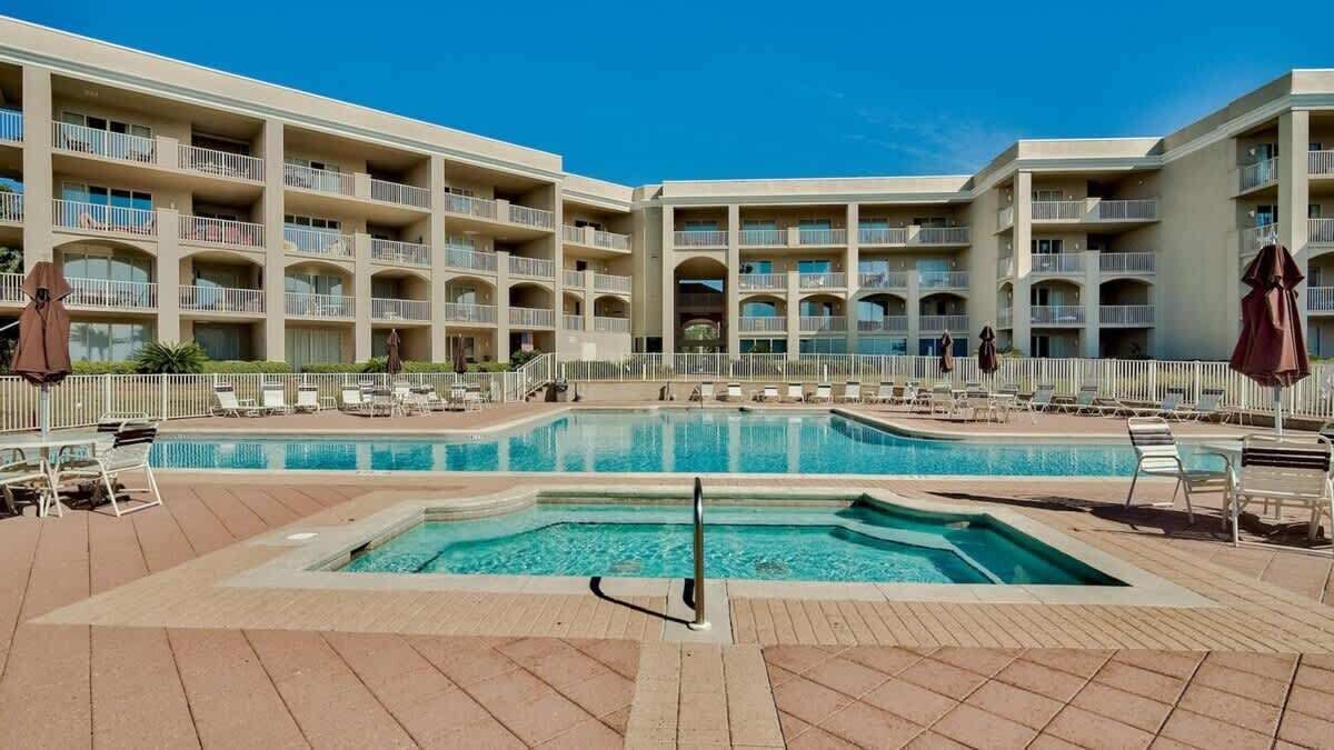 A hotel with multiple balconies, a central swimming pool, and outdoor seating areas.