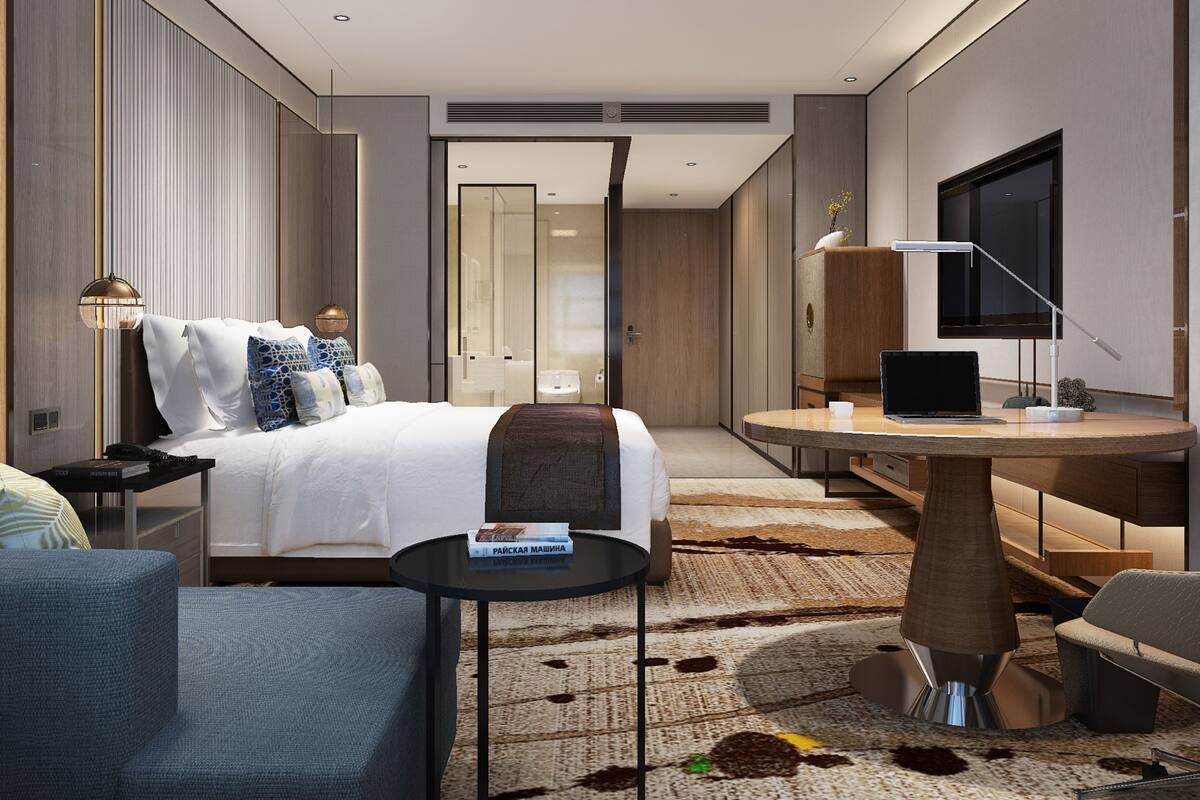 Una habitación de hotel moderna con cama, escritorio, silla, televisión y una mesita con un libro.