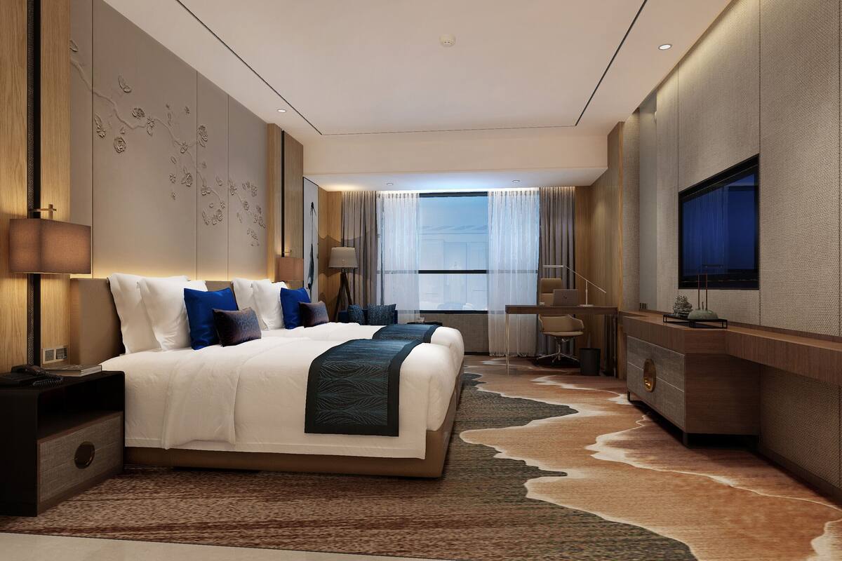 Una habitación de hotel moderna con una cama grande, un escritorio, un televisor y vistas a la ciudad.