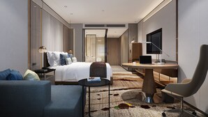 Une chambre d’hôtel moderne équipée d’un lit, d’un bureau avec un ordinateur portable, d’une chaise, d’un canapé et d’une télévision.
