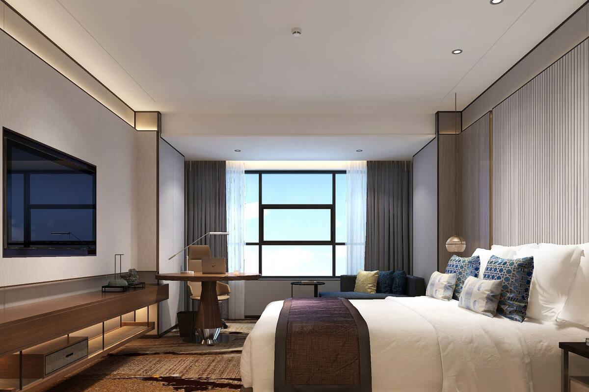 Una habitación de hotel moderna con una cama grande, un escritorio y una televisión montada en la pared.