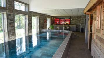 Relax by the pool surrounded by a bar area and large windows.