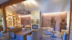 A modern living room with a stone fireplace, leather sofas, and a bear sculpture. - BigRiverCamp Hotel & Spa (Föllinge)