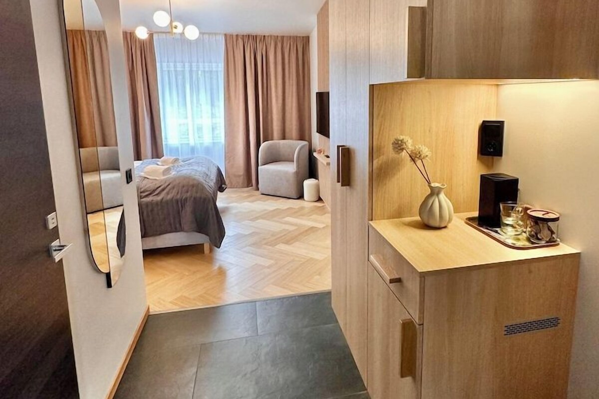 Une chambre d’hôtel moderne équipée d’un lit, d’un bureau, d’une chaise, d’un miroir et offrant une vue sur l’extérieur.