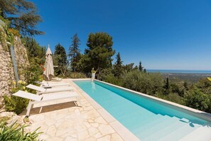 A swimming pool with lounge chairs, a stone wall, and a view of the landscape. - Villa Lemorè - Luxury villa in Puglia with seaview and private pool (Fasano)