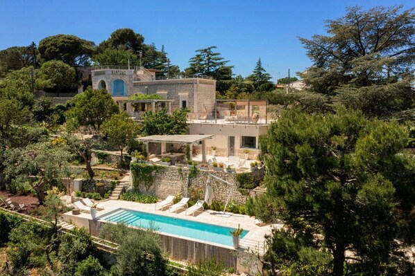 A villa with a swimming pool, outdoor seating, and a stone building with arches. - Villa Lemorè - Luxury villa in Puglia with seaview and private pool (Fasano)