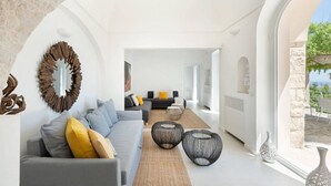 Ein modernes Wohnzimmer mit einem grauen Sofa, gelben Kissen und einem gewebten Couchtisch.