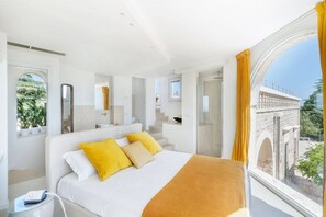 A modern hotel room with a large bed, a glass side table, a mirror, and a view of a bridge and greenery outside. - Villa Lemorè - Luxury villa in Puglia with seaview and private pool (Fasano)