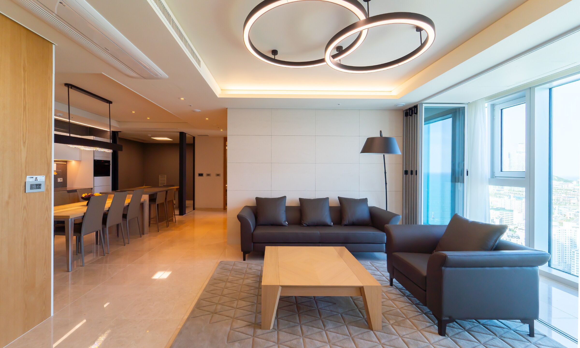 A modern living room with a sofa, coffee table, and a dining area with chairs and a table.
