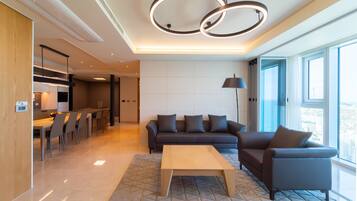 A modern living room with a sofa, coffee table, and a dining area with chairs and a table.