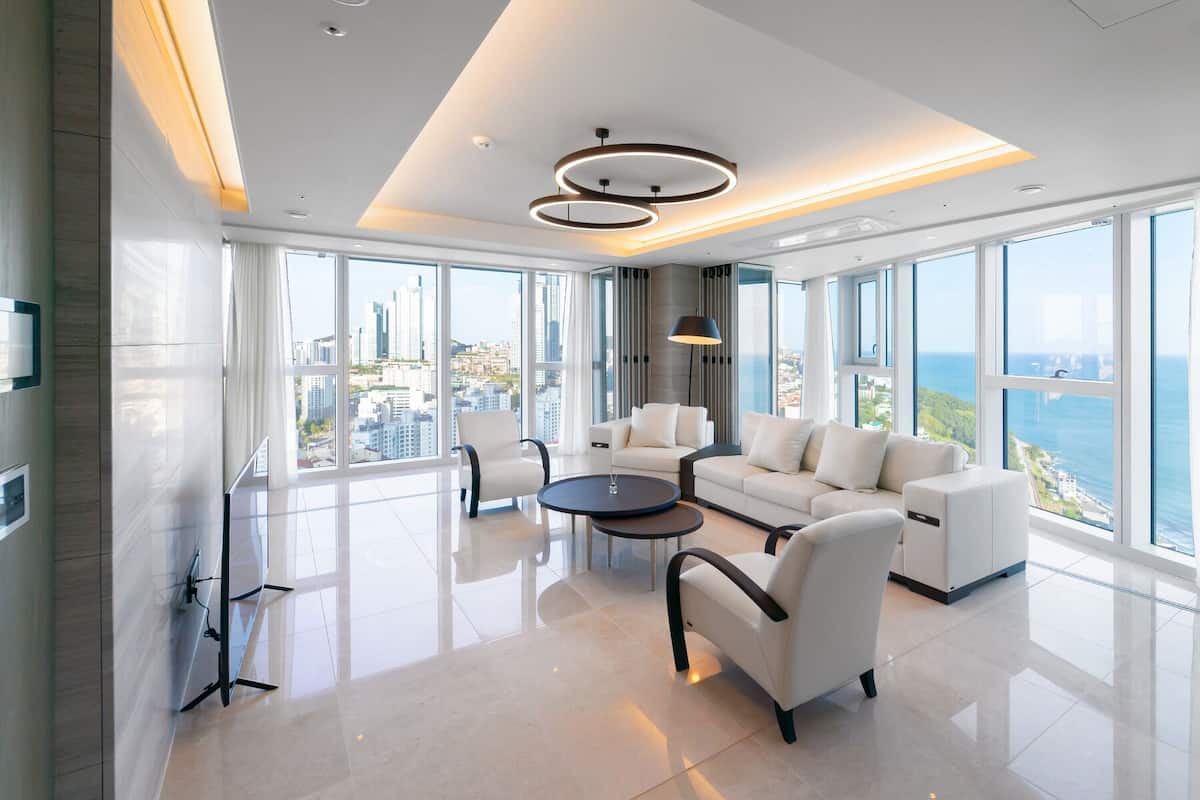 Un salón moderno con vista a la ciudad, una mesa de centro redonda y un ventanal grande.