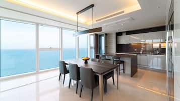 A modern kitchen with a view of the sea, a dining area with a table and chairs, and a large window.