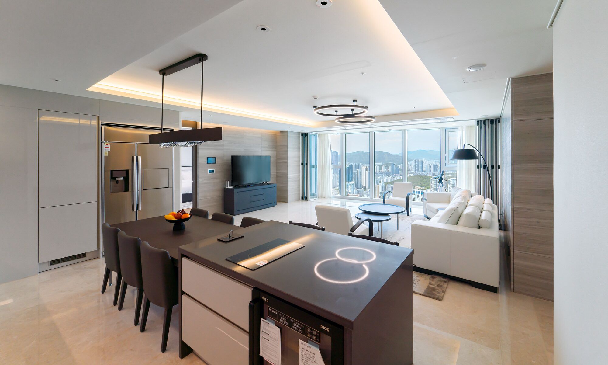 Una habitación de hotel moderna con cocina, comedor y sala de estar con vista a la ciudad.