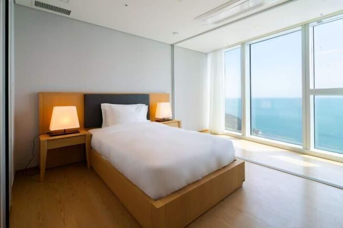 Una habitación de hotel moderna con una cama grande, dos lámparas de noche y vista al océano.