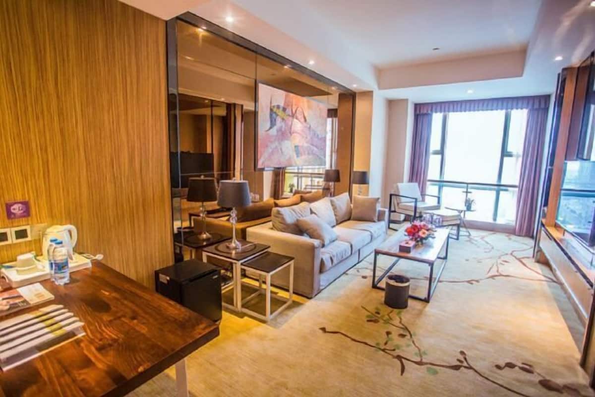 A modern hotel room with a sofa, coffee table, and a large window.