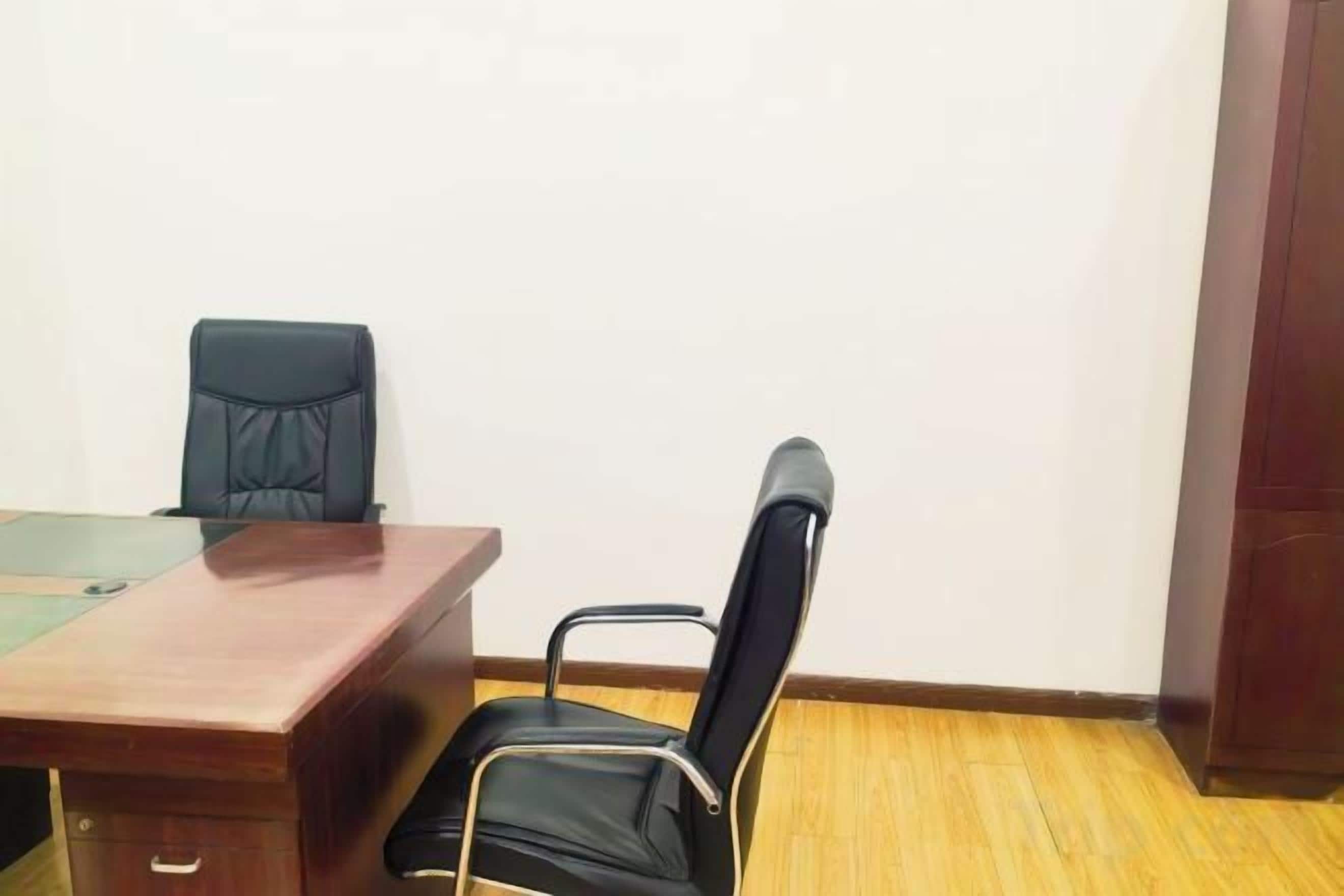 A conference room with a wooden table, two black chairs, and a white wall.