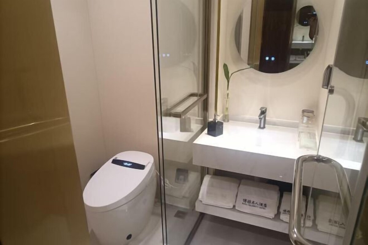 A modern bathroom with a toilet, a glass shower enclosure, a sink, and a mirror.